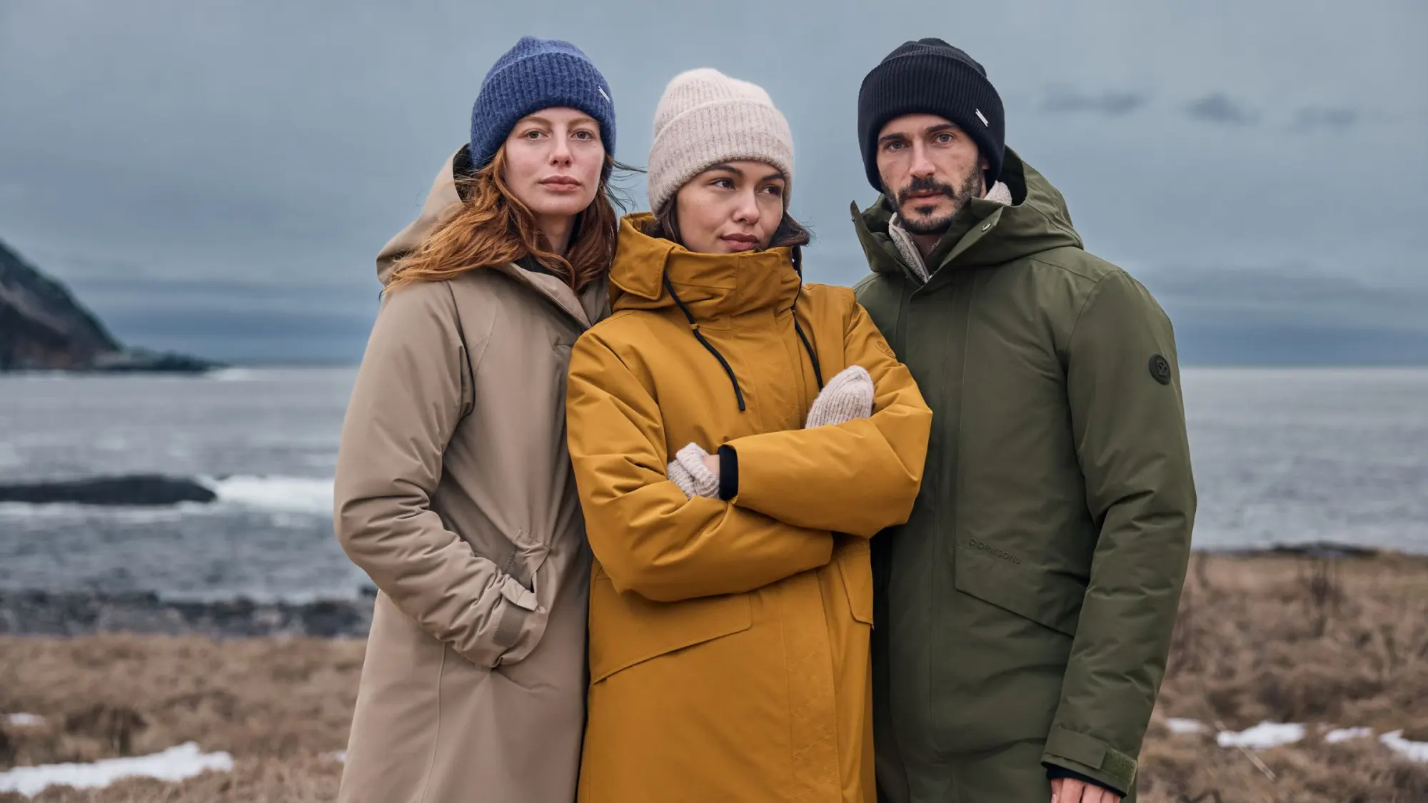 Tre vänner i parkas vid havet